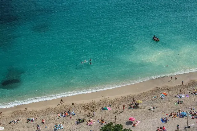 Aerial view of a sunny beach with swimmers and people on towels